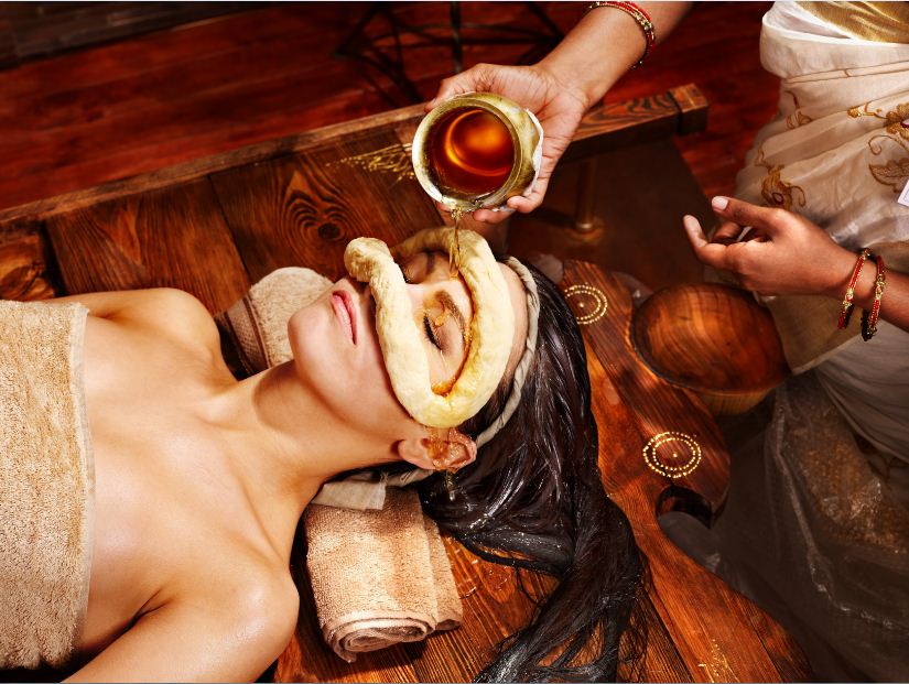 An Ayurvedic shirodhara treatment being administered to a patient at Cherian Ashram